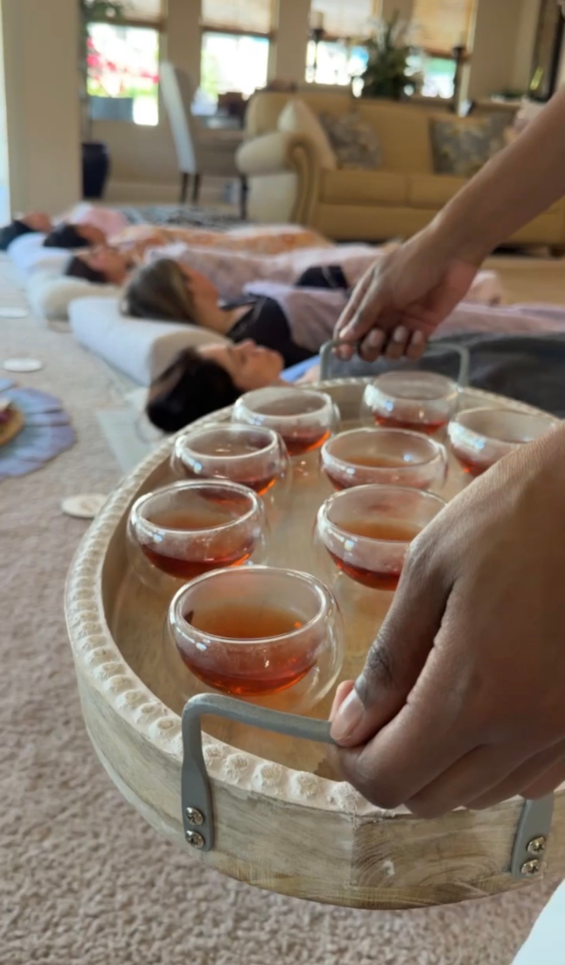 A wooden tray of glass tea cups being served during a Casa Yogita tea ritual